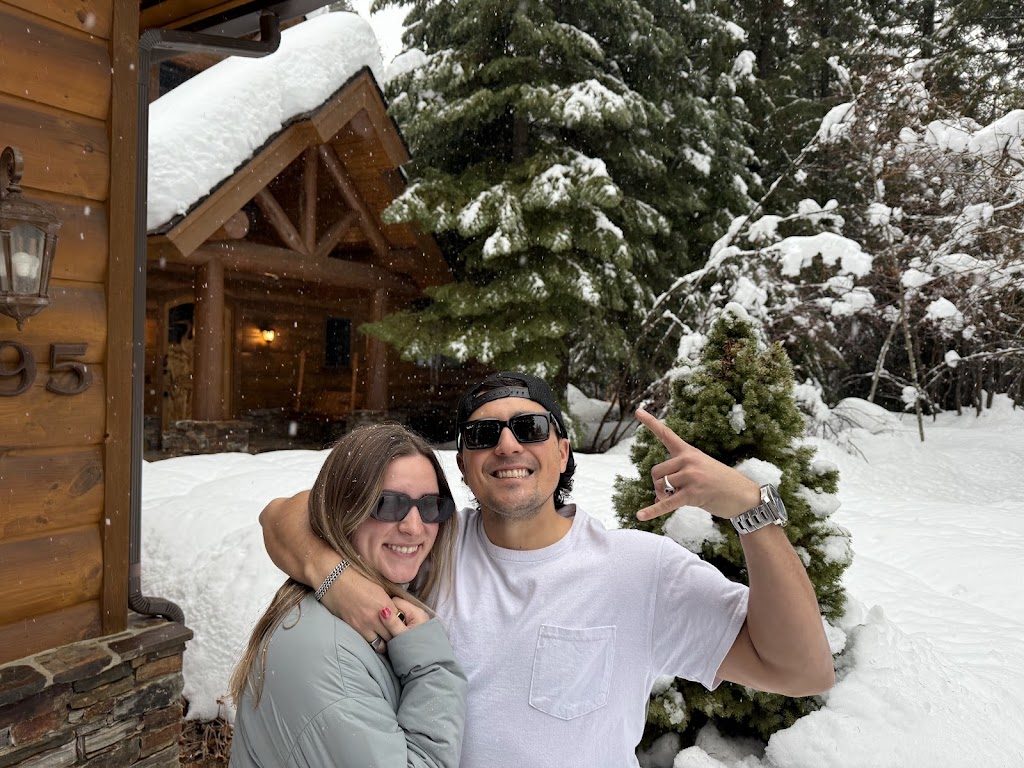 Akylah and Chad in deep snow outside a log cabin
