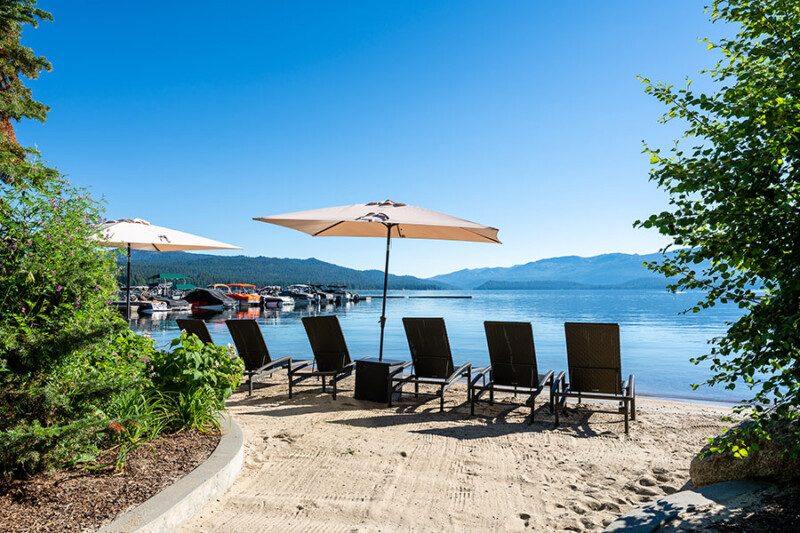 Lounge chairs and umbrellas on a sandy beach facing the lake